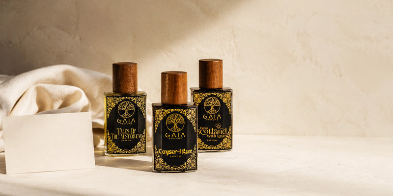 Three GAIA perfume bottles with wooden caps on a light background. About Us Page, GAIA PArfums