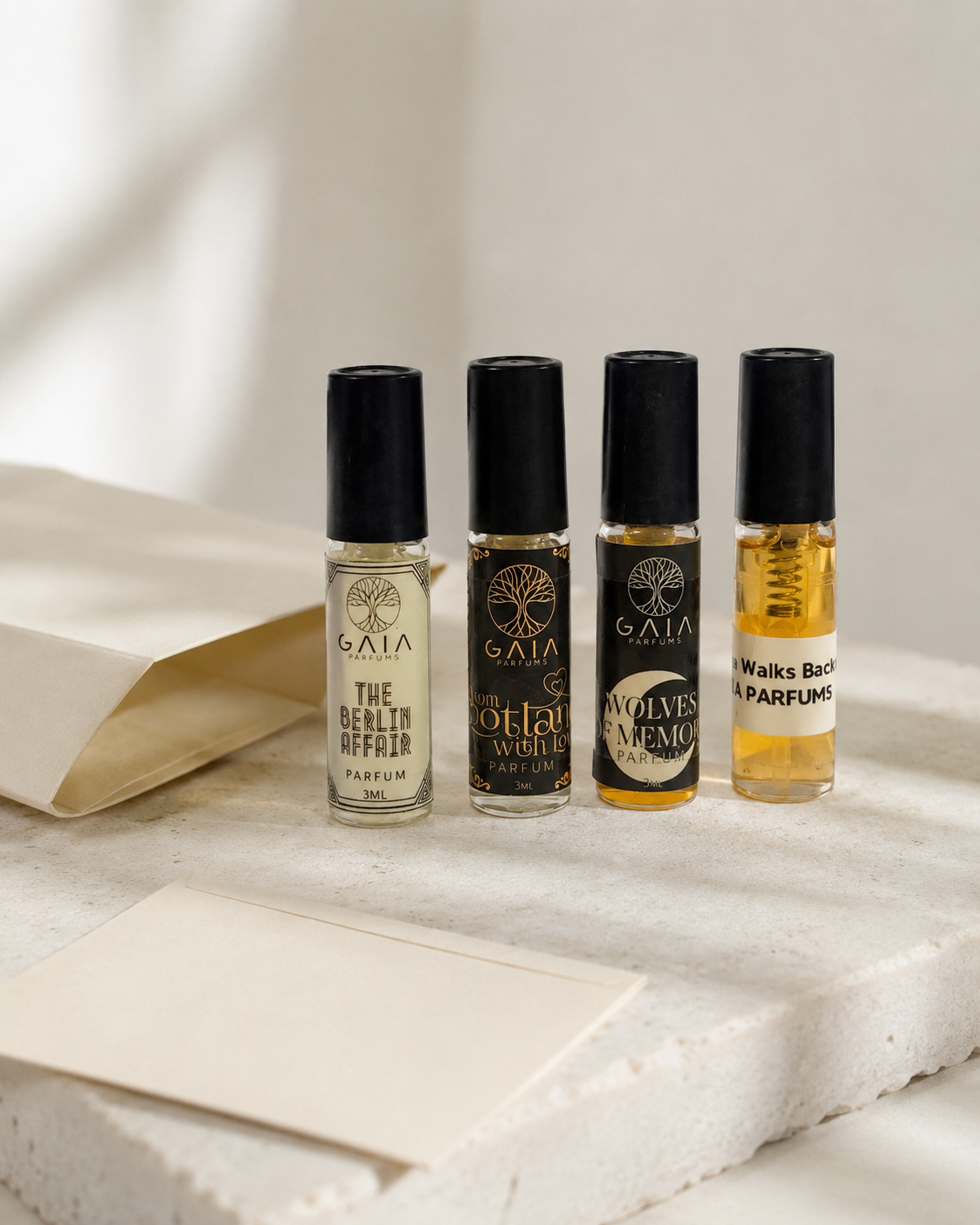 The GAIA Parfums 4 sample vials from Discovery Set styled with cream cards / soft shadow / light stone surface.
