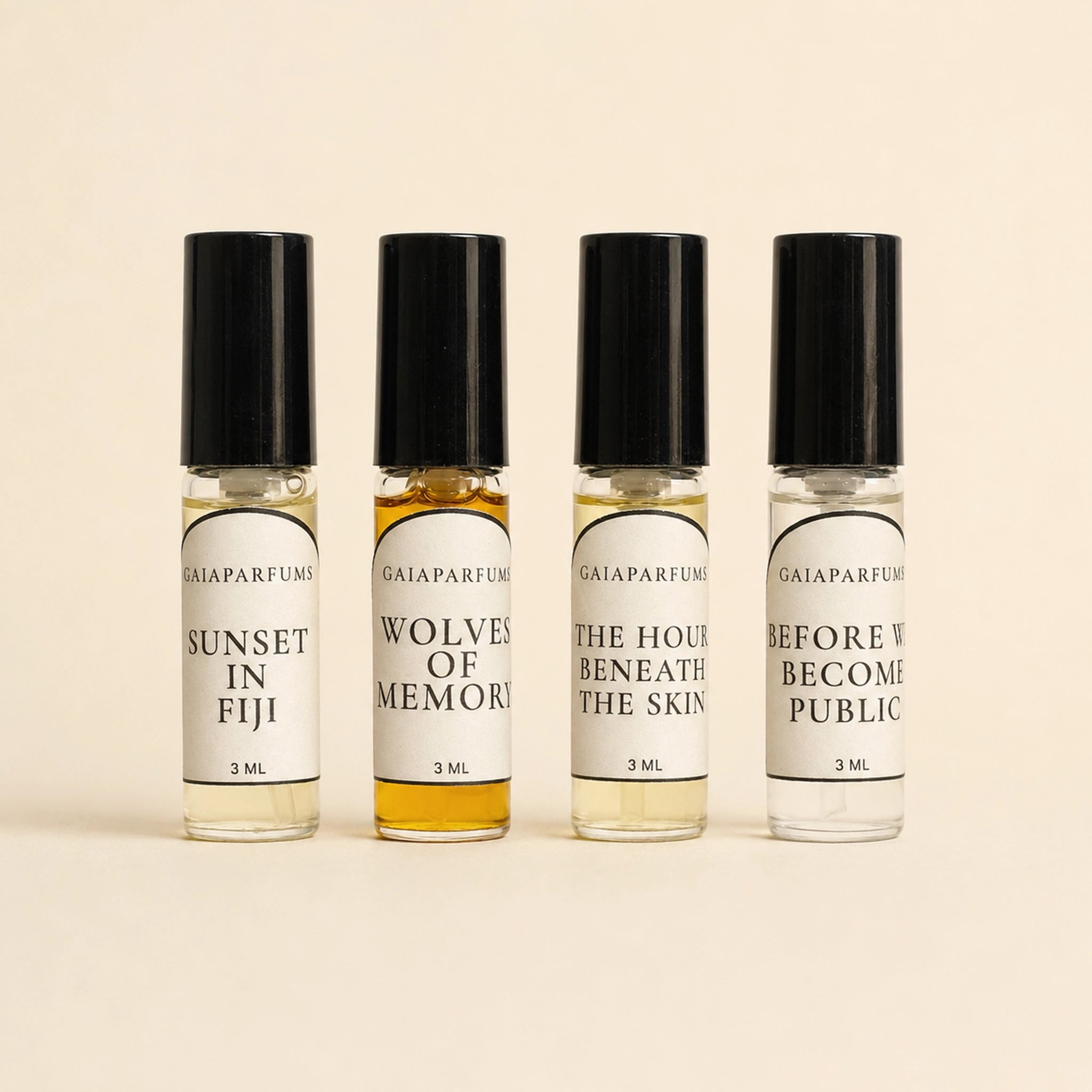 Four 3ml perfume bottles with black caps and white labels, arranged in a row on a light beige background. The labels read GAIA Parfums, and the fragrances are Sunset in Fiji, Wolves of Memory, The Hour Beneath the Skin, and Before We Become Public.
