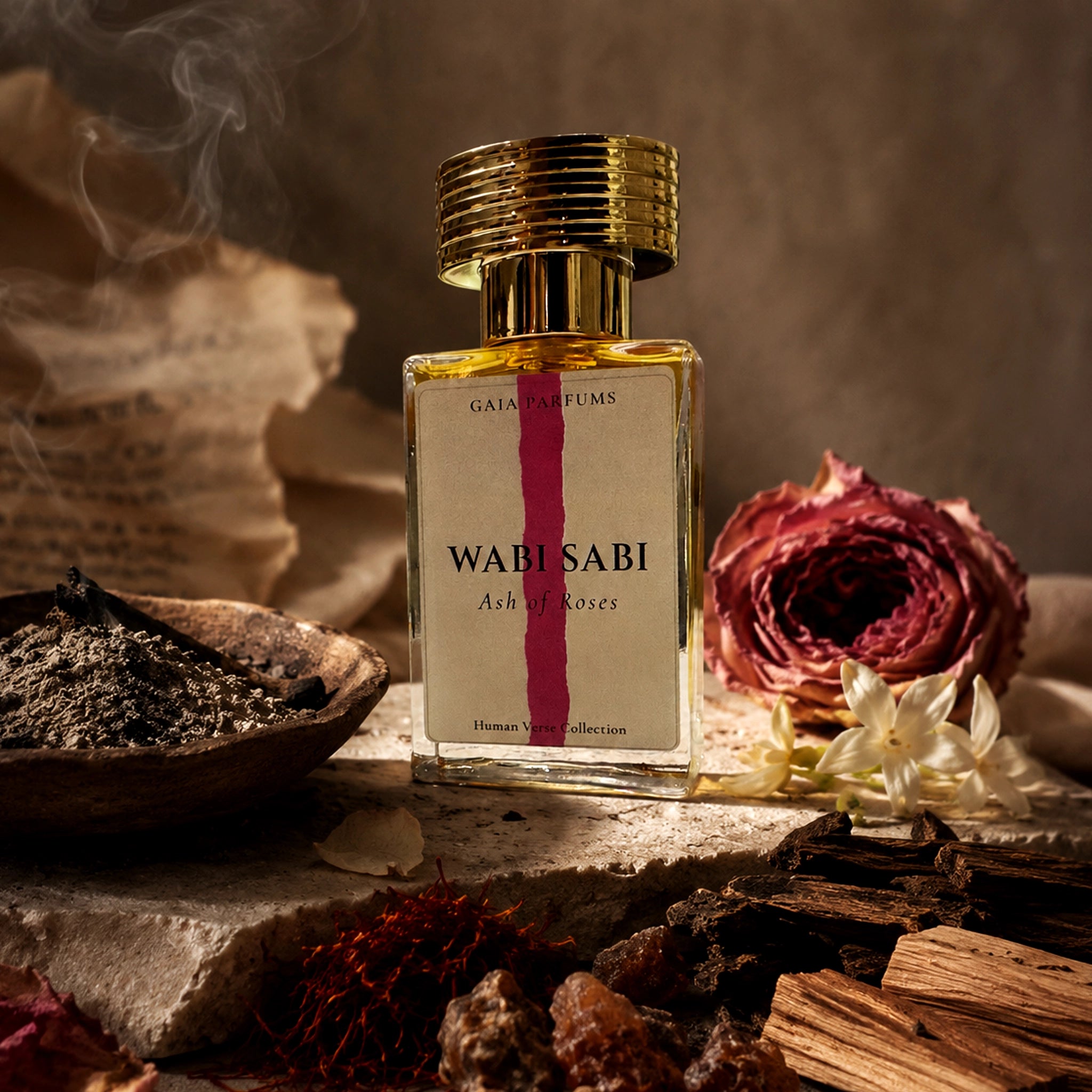 A bottle of GAIA Parfums Wabi Sabi Ash of Roses fragrance, styled with dried flowers, incense, and wood on a rustic stone surface.